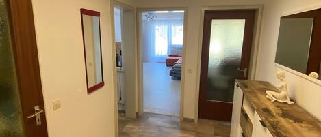 Un pasillo con una lámpara moderna, un espejo y una puerta de madera.