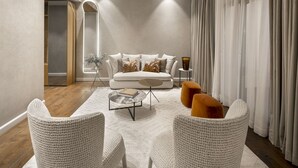 Una sala de estar moderna con un sofá blanco, dos sillones, una mesa de centro y una mesita de noche con un jarrón.