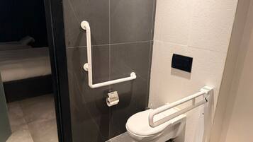 A modern bathroom with a toilet, grab bars, and a shower area.