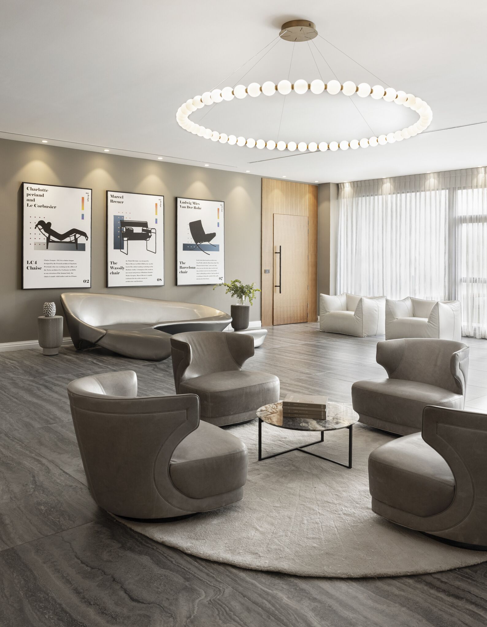 Un área de lounge moderna con una disposición circular de asientos, una mesa de centro y una lámpara de araña contemporánea.