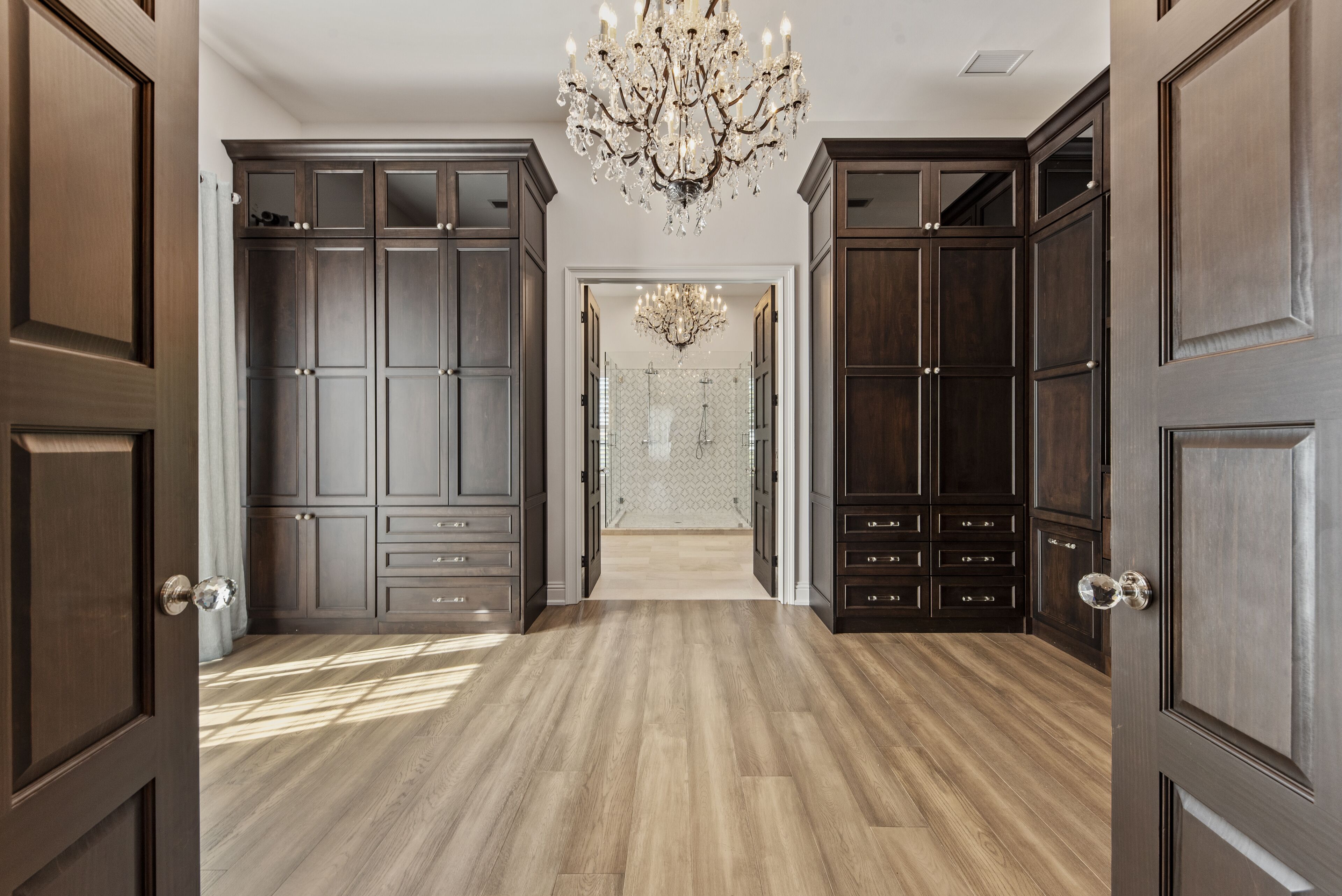 A hallway with dark wood cabinets and a chandelier.