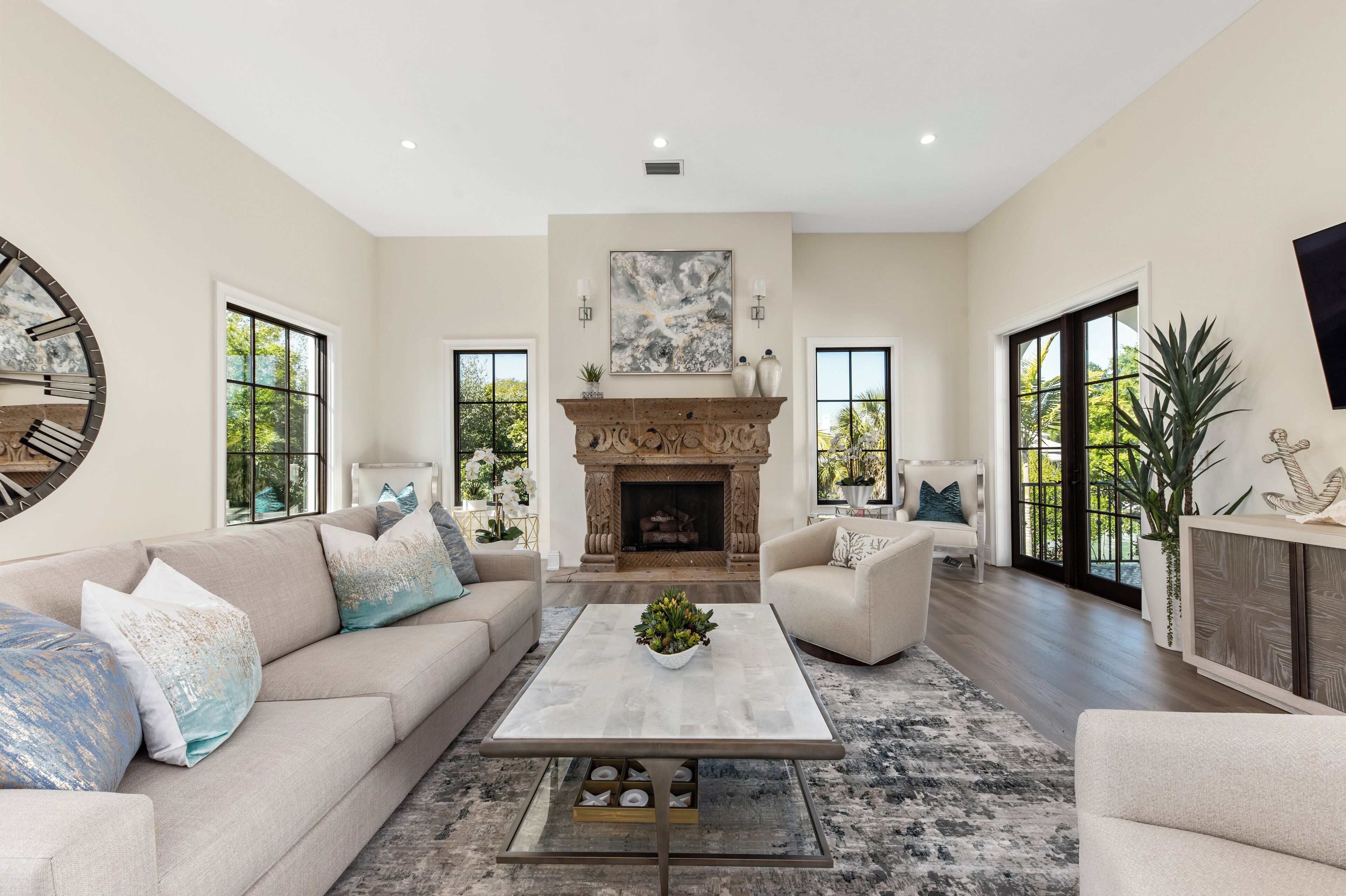 A spacious living room with a fireplace, two sofas, a coffee table, and large windows.