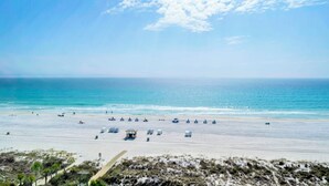 A beach with a clear sky, a sandy shore, and a few beach chairs and umbrellas. - 🌴Gulf Views- Beachside Pool- Studio Top of the Gulf 813🌴 (Panama City Beach)