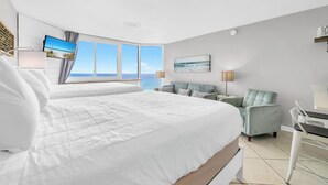 A modern hotel room with a large bed, a seating area, a television, and a view of the sea. - 🌴Gulf Views- Beachside Pool- Studio Top of the Gulf 813🌴 (Panama City Beach)