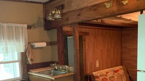 Une cuisine de taille réduite avec des murs en bois, un évier et une table à manger.
