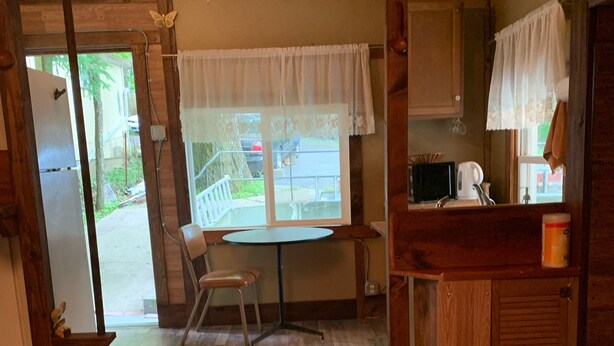Un intérieur en bois comprenant un coin repas, une cuisine et une vue sur l’extérieur.