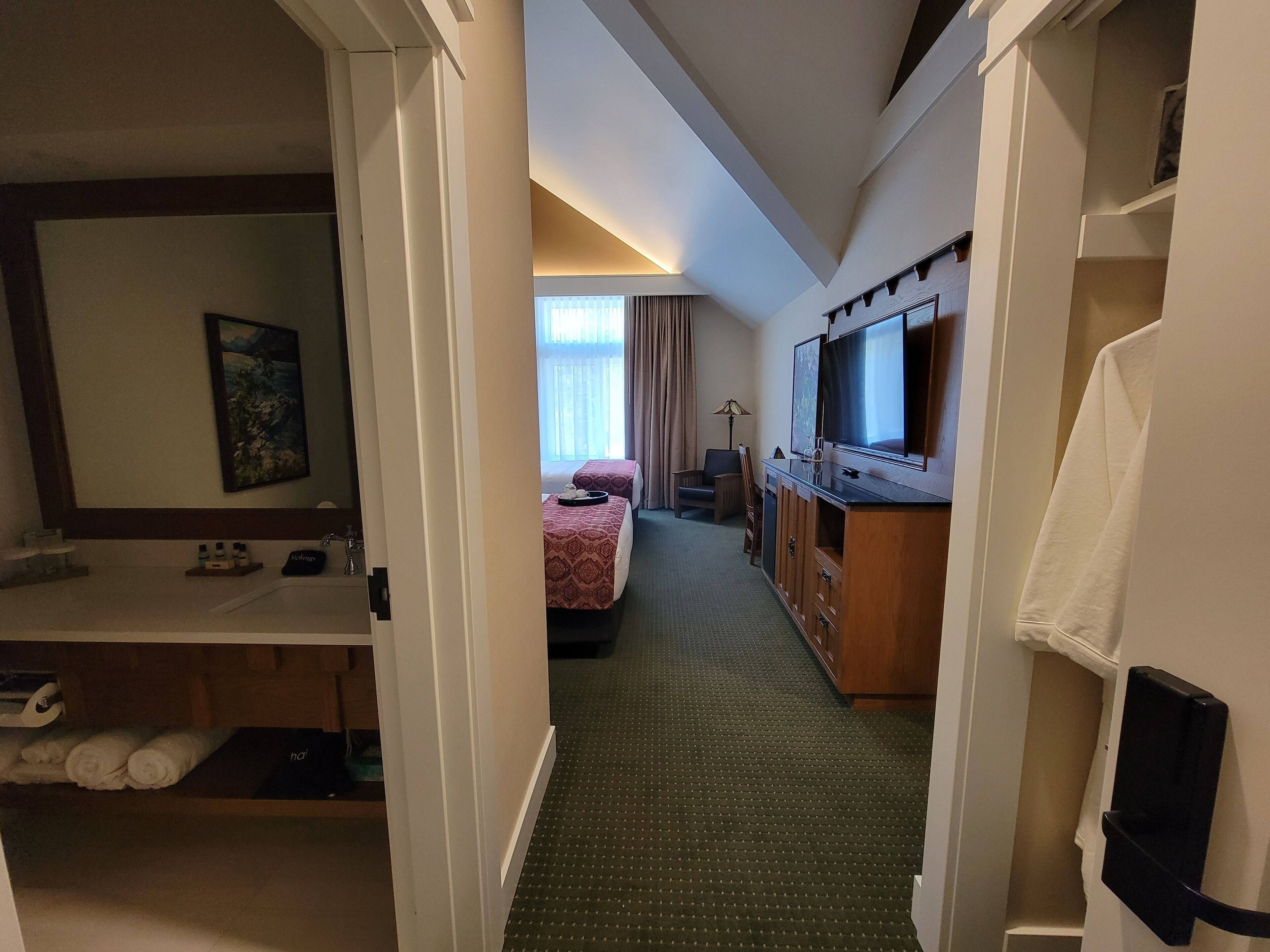 Une chambre d’hôtel équipée d’un lit, d’un bureau, d’une télévision et d’une salle de bain avec un lavabo et un miroir.