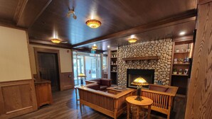 A cozy lobby with wooden furniture, a stone wall fireplace, and a wooden ceiling. - Kilmorey Lodge (Waterton Park)
