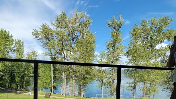 A wooden deck with a view of a lake and trees. - Kilmorey Lodge (Waterton Park)