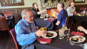 A group of people dining at a restaurant with stone wall decor and a fireplace. - Kilmorey Lodge (Waterton Park)