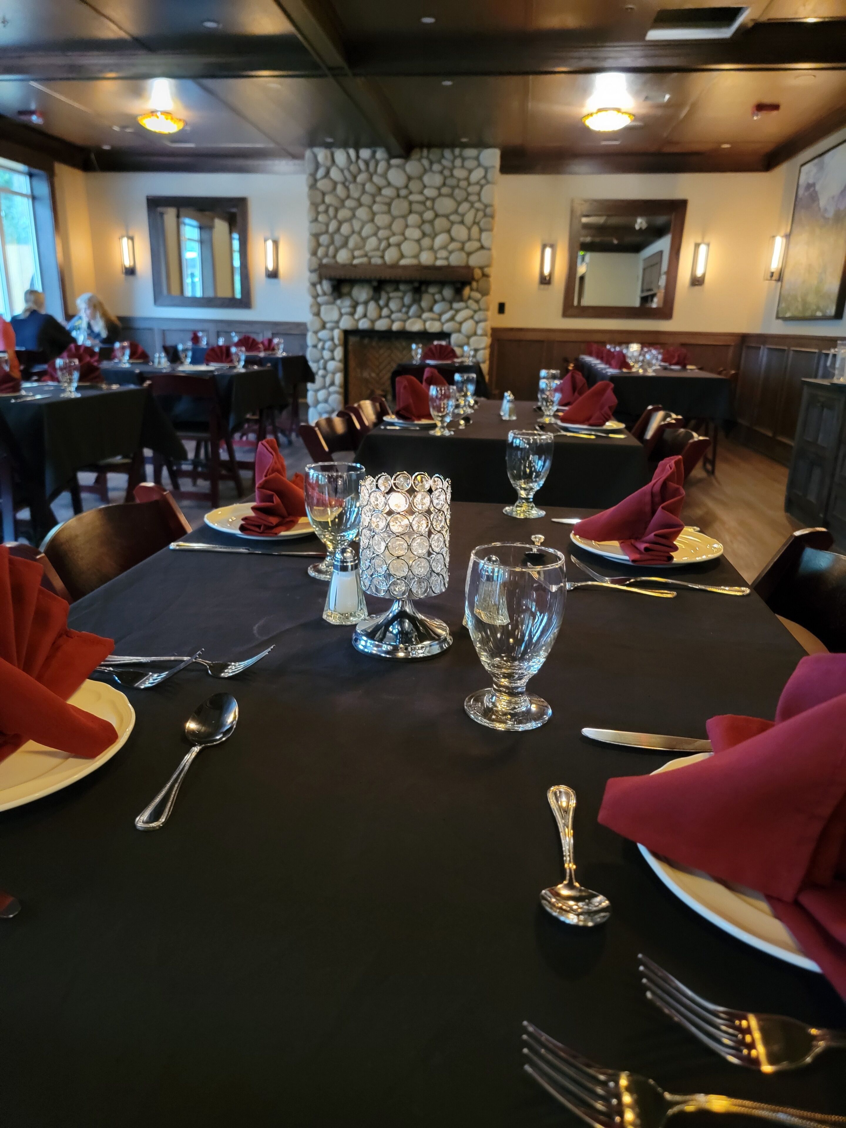 Un restaurante con mesas dispuestas para comer, que presenta una pared de piedra y una chimenea al fondo.