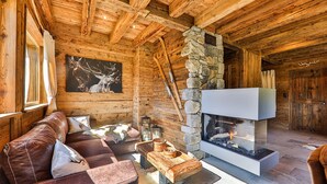 A cozy log cabin interior with a stone fireplace, leather sofa, and rustic decor. - Chalet Hohneck 4**** old wood and stone, SPA, sauna, charging station (Stosswihr)
