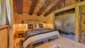 A wooden cabin bedroom with a bed, nightstands, and a large window. - Chalet Hohneck 4**** old wood and stone, SPA, sauna, charging station (Stosswihr)