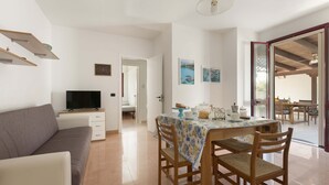 A modern living room with a sofa, TV, dining table, and chairs.