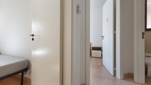 A room with a bed, a white door, and a bathroom visible through an open door.