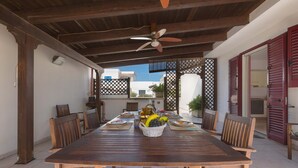 A wooden dining table with chairs, a ceiling fan, and a basket of fruit.