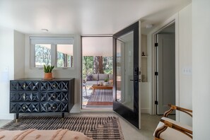 A modern bedroom with a black dresser, a large window, and a sliding glass door leading to a balcony with outdoor seating. - Warm Luxury in walkable downtown Durham (2.5 mi. from Five Pts. Plaza) (Durham)