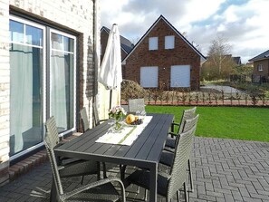 Relax on the patio with a meal set amidst lush surroundings and a brick building in the background.