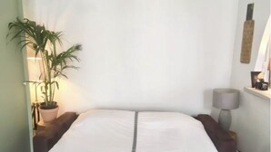 Ein Schlafzimmer mit einem Bett, einer Topfpflanze, einer Lampe und einem Wandregal.