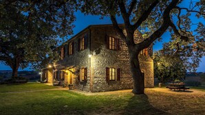 A stone building with multiple windows and a large tree in front.