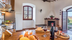 A kitchen with a dining table set for a meal, a fireplace, and a view of the outdoors.