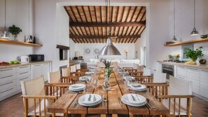 Un comedor amplio con una mesa de madera dispuesta para una comida, rodeado de sillas.
