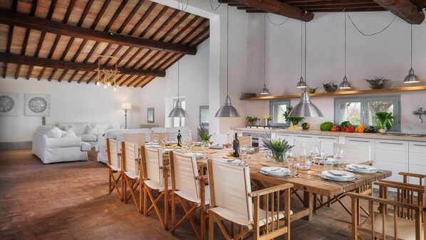 A spacious dining area with a long wooden table set for a meal, surrounded by wooden chairs.