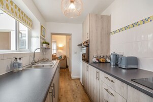 Una cocina moderna con un armario de madera, un horno empotrado y una encimera con un tostador y un hervidor.