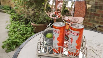 Una mesa con una bandeja metálica que sostiene dos latas de ginebra tónica, una lima y dos vasos.