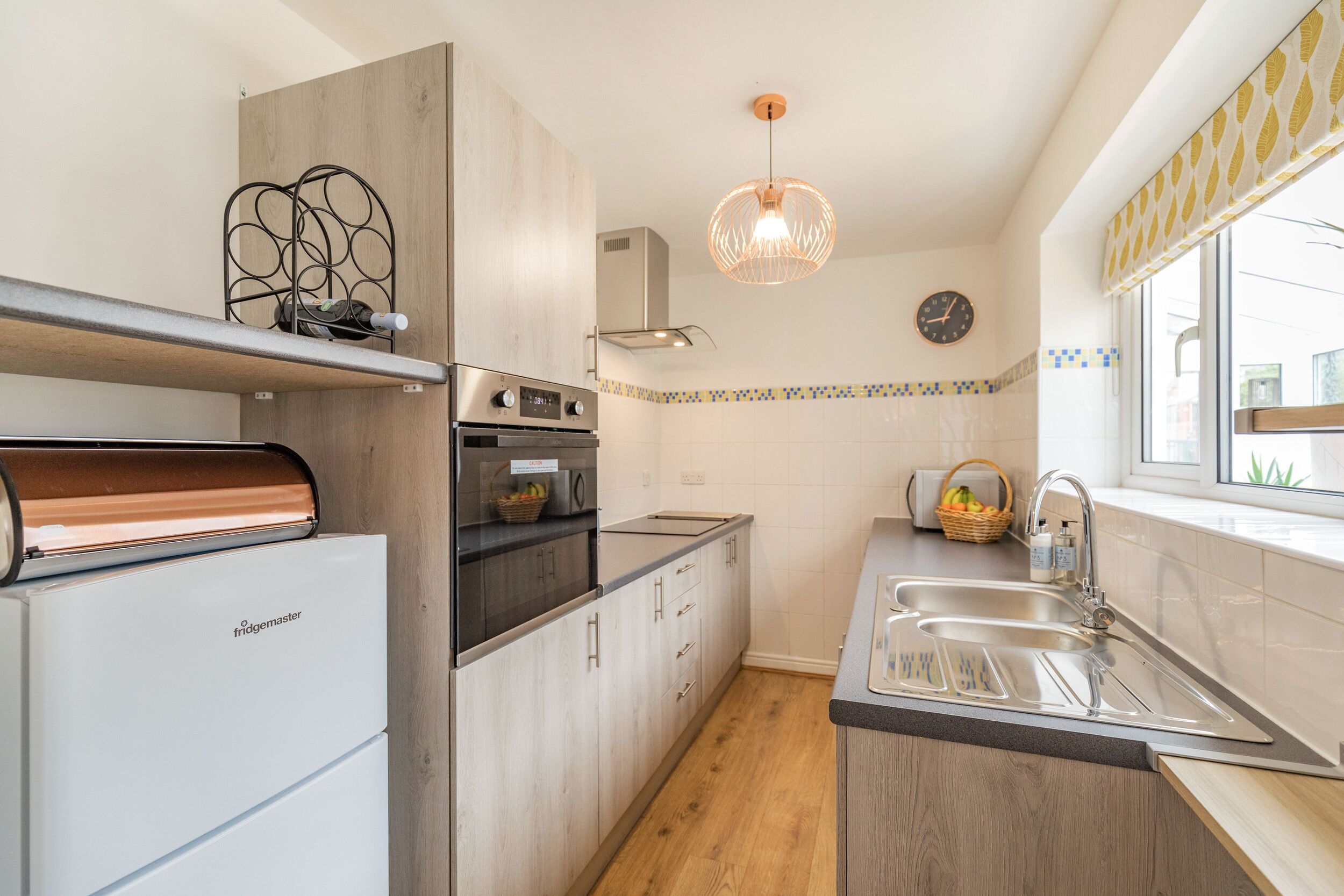 A modern kitchen with a built-in oven, a refrigerator, and a sink.