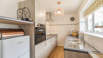A modern kitchen with a built-in oven, a refrigerator, and a sink.