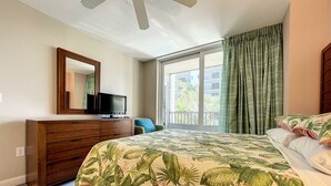 A bedroom with a bed, a dresser, a television, and a window with curtains.