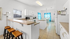 A modern kitchen with white cabinets, a wooden island with stools, a microwave, and a refrigerator. - Private Pool & Spa! Gated Community! Magical Memories! 117 (Davenport)