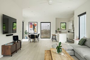 A modern living room with a flat-screen TV, a wooden coffee table, and a sofa. - East Austin Oasis / Pool / Grill / Modern 4BR Home (Austin)