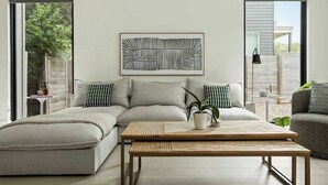 Een moderne woonkamer met een bank, een salontafel en een groot abstract schilderij aan de muur.