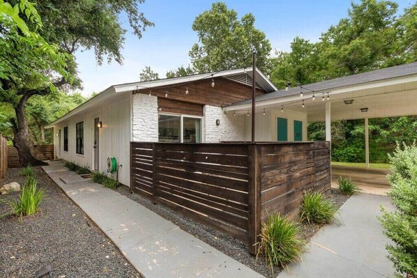 A modern house with a white exterior, a wooden fence, and a covered patio area.