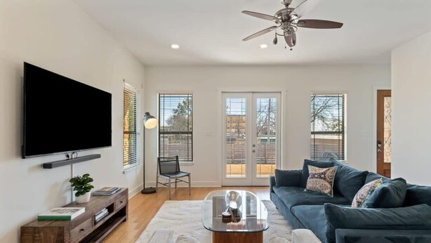 A living room with a flat-screen TV, a coffee table, a sofa, and a ceiling fan. - Bright 3BR Home / East ATX / Cowboy Pool / Near UT (Austin)