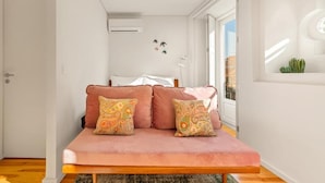A modern bedroom with a pink sofa, decorative pillows, a bed, and a window with a view. - Captivate Studio w/ Balcony | Clérigos by HostWise (Porto)