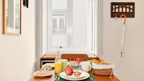 A breakfast setup with a table, plates, a basket of bread, and a bottle of orange juice. - Captivate Studio w/ Balcony | Clérigos by HostWise (Porto)