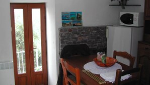 Un comedor con una mesa de madera, sillas, un refrigerador blanco, un microondas y una chimenea de piedra.