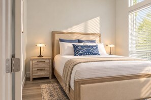 Een slaapkamer met een bed, twee nachtkastjes, een raam met zonwering en een deur.