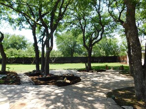 Enjoy a serene outdoor space with a paved walkway, shaded by trees and a neatly manicured lawn.