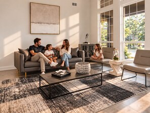 Een moderne woonkamer met een grijze bank, een salontafel en een groot raam.