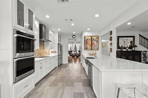 Enjoy meals in the spacious kitchen with a large island, sink, and bar stools, and dine in the adjacent area with a chandelier.