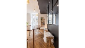 Un espace de salle à manger moderne avec une table et des chaises en bois, un banc recouvert de fourrure et des luminaires suspendus.
