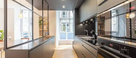 A modern kitchen with a central island, built-in appliances, and a view to the outside.