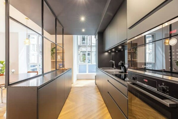 A modern kitchen with a central island, built-in appliances, and a view to the outside.
