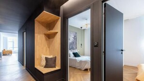 Une chambre moderne dotée d’une banquette intégrée, d’un lit avec une tête de lit et d’une porte donnant sur une autre pièce.