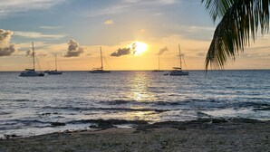 A sunset over a calm sea with several sailboats. - Luxury Living with beautiful ocean and sunset views (Frederiksted)
