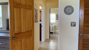 A hallway with a wooden door, a wall-mounted decorative piece, and a white crib in the background. - Luxury Living with beautiful ocean and sunset views (Frederiksted)